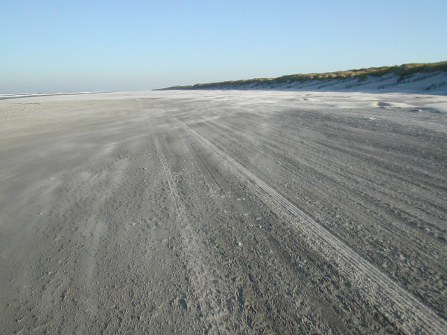 Zand stuift over het strand