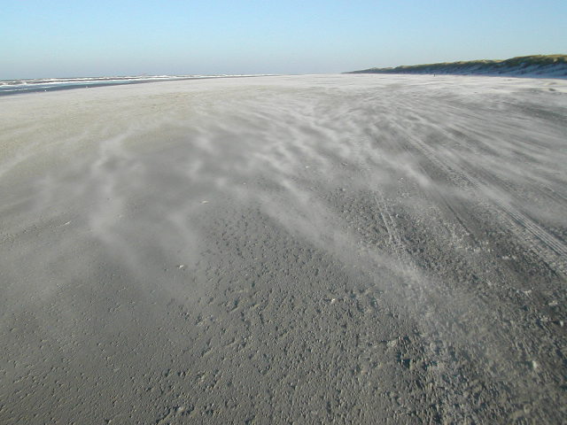 Zand stuift over het strand