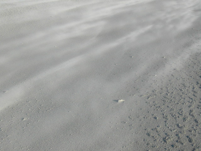 Zand stuift over het strand