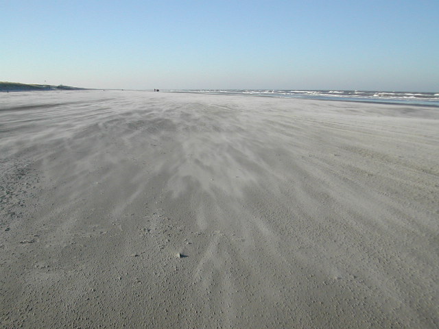 Zand stuift over het strand